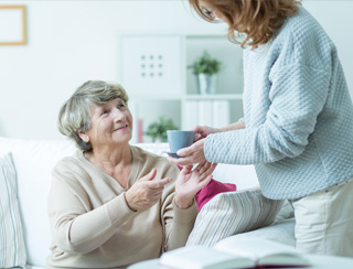 in home care professional serves an elderly woman tea